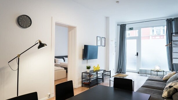 A modern living room with a sofa, a dining table, and a TV. - Great Apartment in Berlin Neukölln (Berlin)