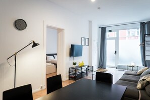A modern living room with a sofa, a dining table, and a TV. - Great Apartment in Berlin Neukölln (Berlin)