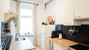 A modern kitchen with a wooden countertop, a black tiled backsplash, a white refrigerator, and a coffee machine. - Great Apartment in Berlin Neukölln (Berlin)