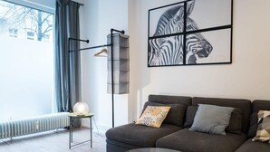 A modern living room with a dark grey sofa, a glass coffee table, and a zebra-themed artwork on the wall. - Great Apartment in Berlin Neukölln (Berlin)