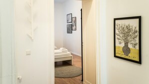 A hallway with a bed, a framed artwork, and a door leading to another room. - Great Apartment in Berlin Neukölln (Berlin)