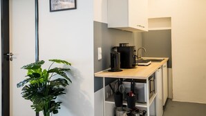 Een kleine keuken met een koffiezetapparaat, spoelbak en opbergkasten.