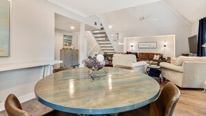 A spacious living room with a round dining table, a staircase, and a cozy seating area.