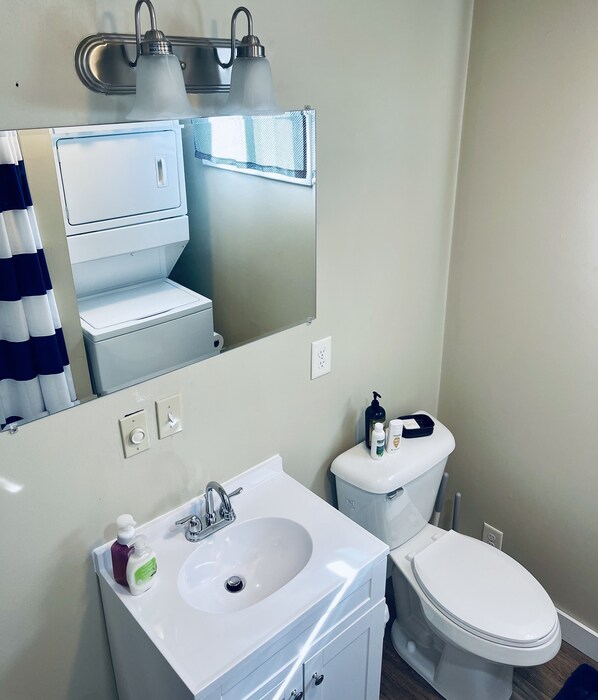 A bathroom with a white sink, mirror, and toilet. There are two wall-mounted lights above the mirror, and a towel rack is visible. - Split Pine a Delightful Cozy Space (Thompson)