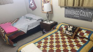 Une chambre avec deux lits, une table de chevet, une lampe et un panneau mural indiquant l’emplacement dans le comté de Winnebago, dans l’Iowa.
