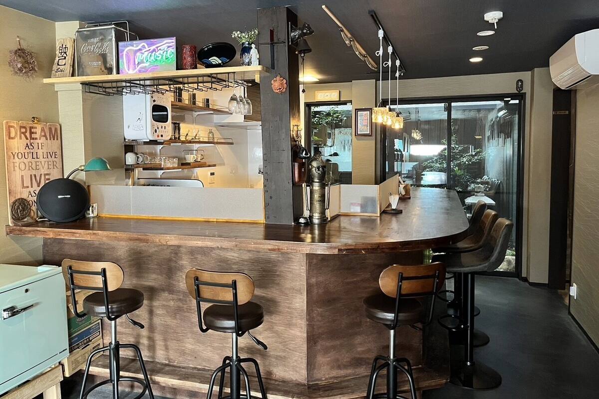 A modern kitchen with a bar area, bar stools, and a view of the outdoors.