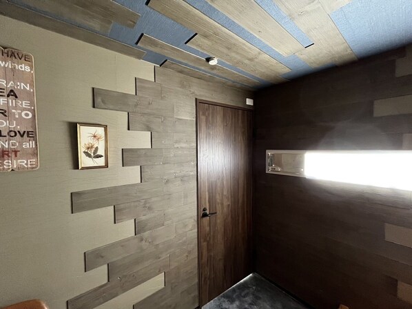 Ein Zimmer mit Holztür, einem gerahmten Bild und einer Wandleuchte.