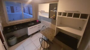 A compact kitchen with a window, a stove, and a sink. - Cobertura Duplex - Santos (Santos)