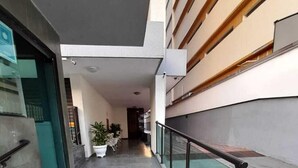 A corridor with a tiled floor, potted plants, and a glass railing. - Cobertura Duplex - Santos (Santos)