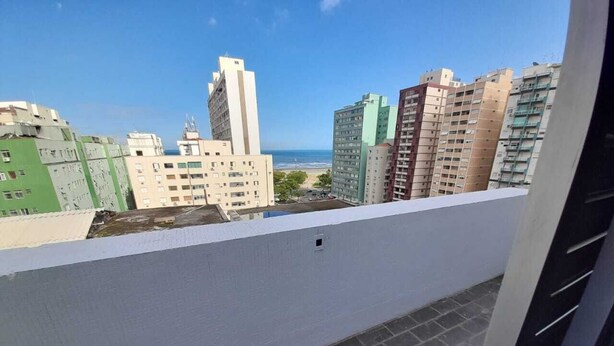 A balcony with a view of high-rise buildings and a beach. - Cobertura Duplex - Santos (Santos)