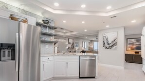 Una cocina moderna con armarios blancos, electrodomésticos de acero inoxidable y una isla central.