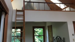 A loft bedroom with a wooden ceiling, skylights, a bunk bed, a ladder, and a window with a view of trees. - •1898UrbanVictorian Loft view near Convention Ctr. (Portland)