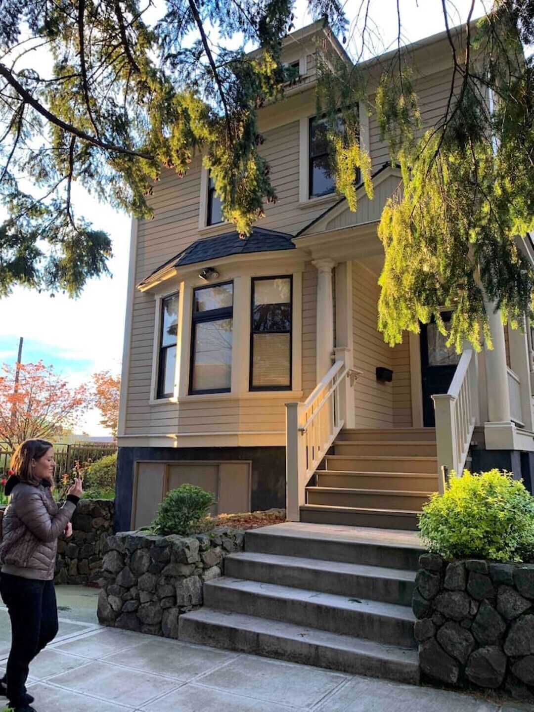 A two-story house with a stone foundation, a front porch, and a staircase leading to the entrance.