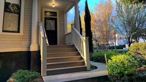 A two-story house with a front porch, a staircase, and a well-maintained garden. - •1898UrbanVictorian Loft view near Convention Ctr. (Portland)