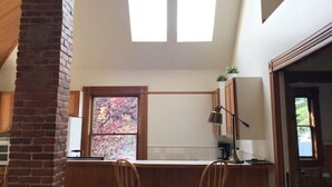 A kitchen with a high ceiling, wooden beams, a brick chimney, and a skylight. - •1898UrbanVictorian Loft view near Convention Ctr. (Portland)