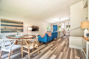 A modern interior with a dining area, a blue sofa, and a kitchen in the background.