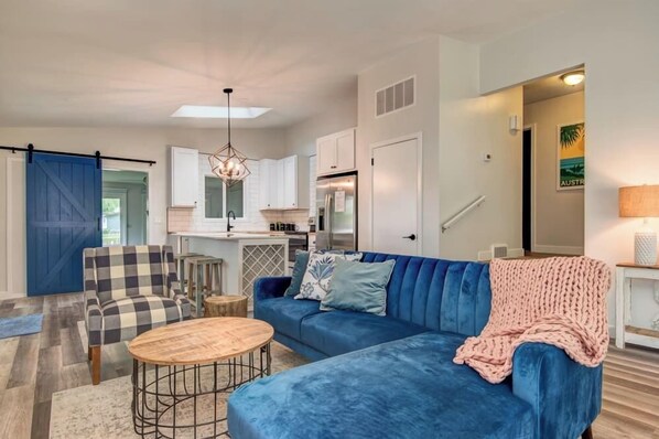A modern living room with a blue sofa, a wooden coffee table, and a checkered armchair. - Boji Waterfront Retreat - Millers Bay Canals (Milford)