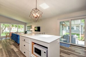 A modern kitchen with a built-in microwave, a hanging light fixture, and a sliding glass door leading to a patio.