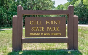 Un letrero de madera con la inscripción 'Gull Point State Park' y 'Departamento de Recursos Naturales'.