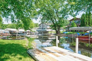 A lakeside dock with boats, a grassy area, and a house in the background. - Boji Waterfront Retreat - Millers Bay Canals (Milford)