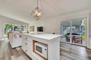 A modern kitchen with a central island, built-in appliances, and a dining area with outdoor seating. - Waterfront Retreat | Millers Bay Canal Getaway (Milford)