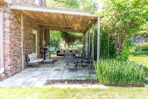 An outdoor patio with a brick wall, covered seating area, and a garden. - Family House (Omaha)