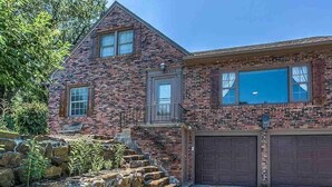 A two-story brick house with a stone staircase leading to a front porch. - Family House (Omaha)