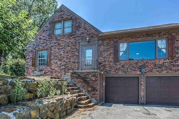 A two-story brick house with a stone staircase leading to a front porch. - Family House (Omaha)
