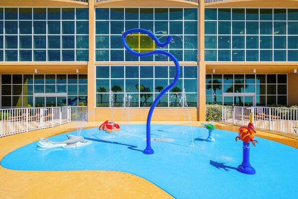 A water play area with a dolphin-shaped slide and a blue water fountain.