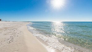 Una playa con aguas cristalinas, una orilla arenosa y un sol brillante.