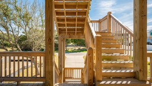 A wooden staircase leading to a covered area with a view of a parking lot and trees. - Beach 45: Large, Modern Home Situated on the Davis Canal, Around 500 Feet to Bea (Oak Island)