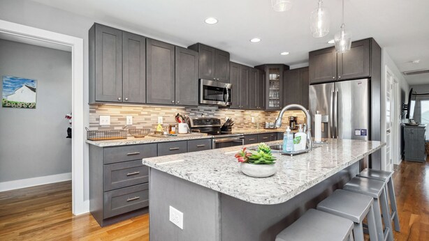 A modern kitchen with grey cabinets, stainless steel appliances, a granite countertop, and bar stools. - Beach 45: Large, Modern Home Situated on the Davis Canal, Around 500 Feet to Bea (Oak Island)