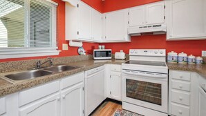 A kitchen with white cabinets, a microwave, a toaster, and an oven.