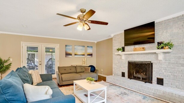 Un salon avec une cheminée, un ventilateur de plafond et un canapé.