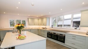 A modern kitchen with a large island, built-in ovens, and a view of the outdoors. - Lea Farm House (Kidderminster)