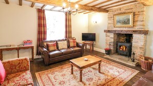 A cozy living room with a fireplace, wooden beams, a leather sofa, and a television. - Lea Farm House (Kidderminster)