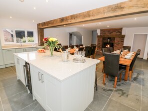 A modern kitchen with a large island, dining area with chairs, and a fireplace.