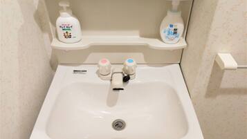 A bathroom sink with two soap dispensers, a faucet, and a toilet paper holder.