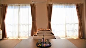 A hotel room with a bed, a table with a tray of amenities, and large windows with curtains. - U-Shuku Fushimi Inari (Kyoto)