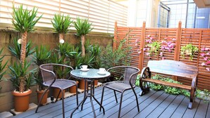 An outdoor patio with a wooden table and chairs, surrounded by potted plants and a wooden fence. - U-Shuku Fushimi Inari (Kyoto)