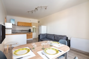A modern kitchen with wooden cabinets, a white refrigerator, and a dining area with a table set for four.