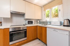 A modern kitchen with white cabinets, a microwave, an oven, a dishwasher, and a coffee maker.