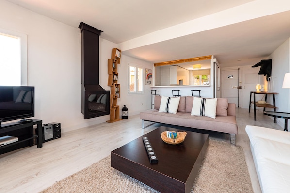 A modern living room with a TV, sofa, coffee table, and fireplace.