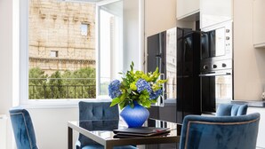 A modern kitchen with black appliances, a dining table with blue chairs, and a vase of flowers. - Amazing 2-bedrooms apartment in front of the Colosseo  (Roma)