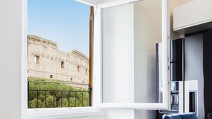A room with a large window overlooking a historic building, a black cabinet, and a blue towel. - Amazing 2-bedrooms apartment in front of the Colosseo  (Roma)