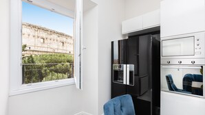 A modern kitchen with a built-in oven, a refrigerator, and a window with a view of a historical building. - Amazing 2-bedrooms apartment in front of the Colosseo  (Roma)