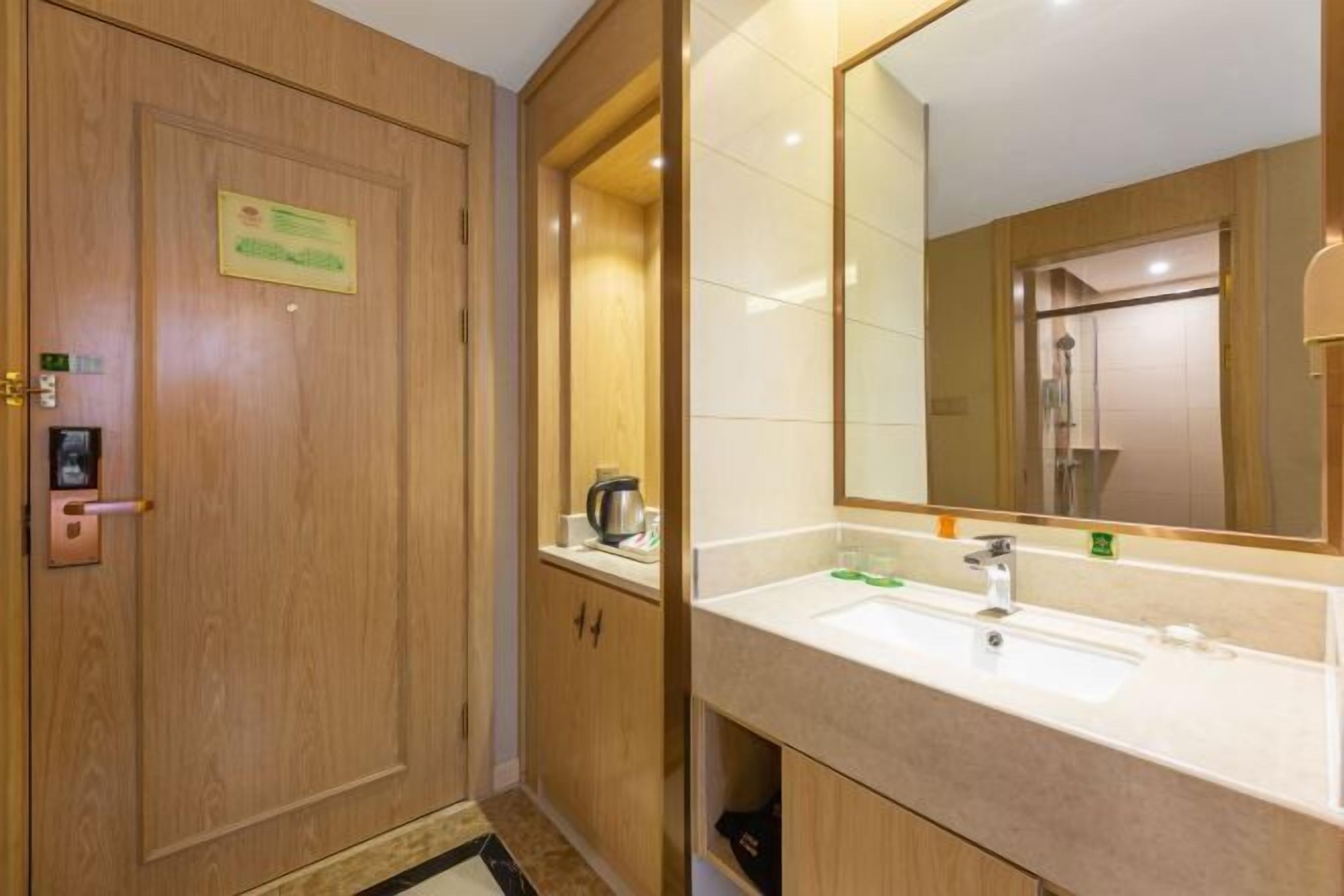 A hotel bathroom with a wooden door, a sink with a mirror, and a shower visible through the glass door.