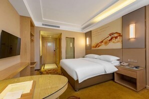 A hotel room with a bed, bedside table, TV, and a wall-mounted light fixture. - Vienna Hotel (Ganzhou Railway Station Wanda Plaza Branch) (Ganzhou)