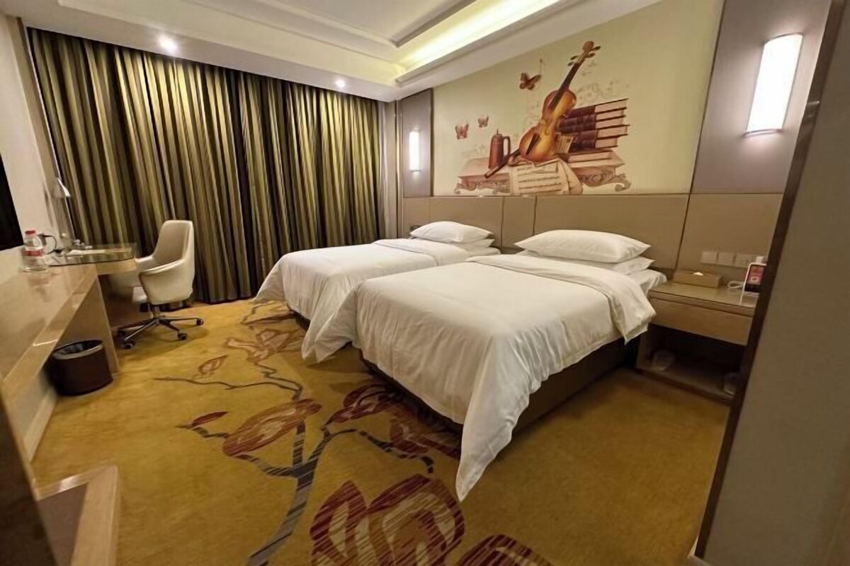 A hotel room with two beds, a desk, and a chair.
