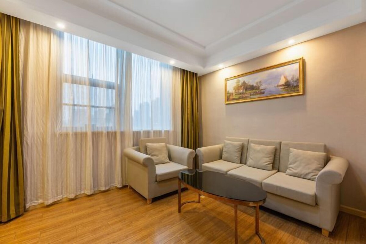A living room with a sofa, armchairs, a coffee table, and a painting on the wall.